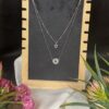 Silver Layered Flower Necklace with crystal pendant displayed on wooden stand